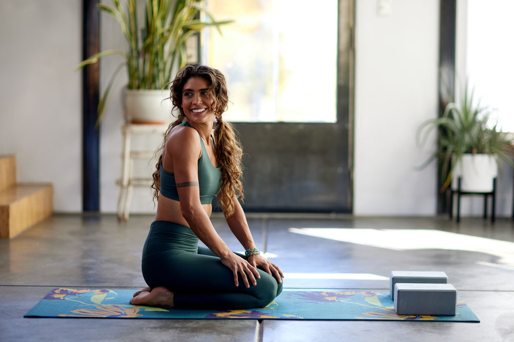 Woman kneeling on yoga mat smiling