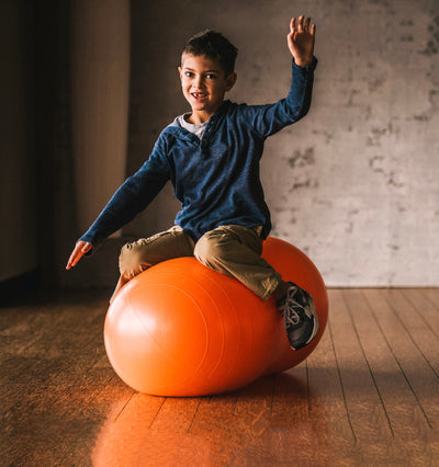 Child sitting on orange Peanut Ball
