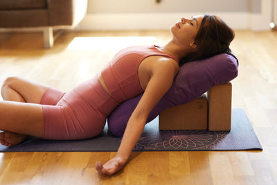 Person in reclined position on bolster and blocks