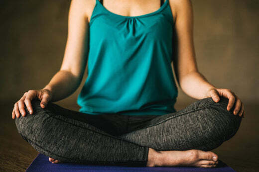 woman in turquoise tank top and yoga pants meditates