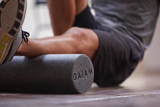 man uses grey foam roller on calf to improve mobility with functional movement