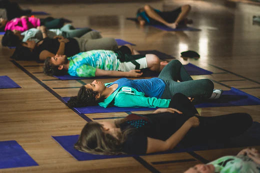 Kids lying on yoga mats in butterfly pose after Gaiam's donation to the local community
