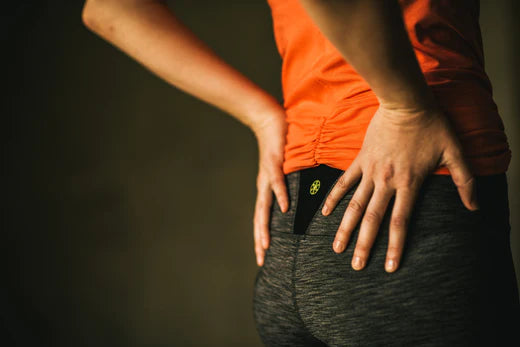 Woman wearing orange workout top holding hips
