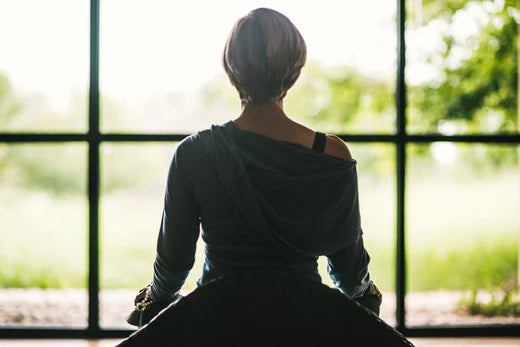 Woman sitting in front of window meditating and living simply