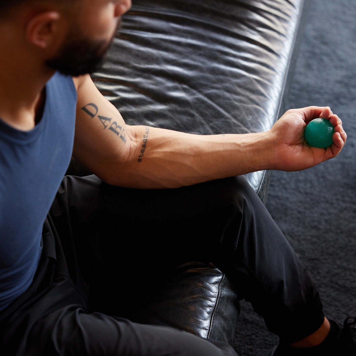 Person holding the teal ball of the Gaiam Restore Hand Therapy Kit in the palm of hand