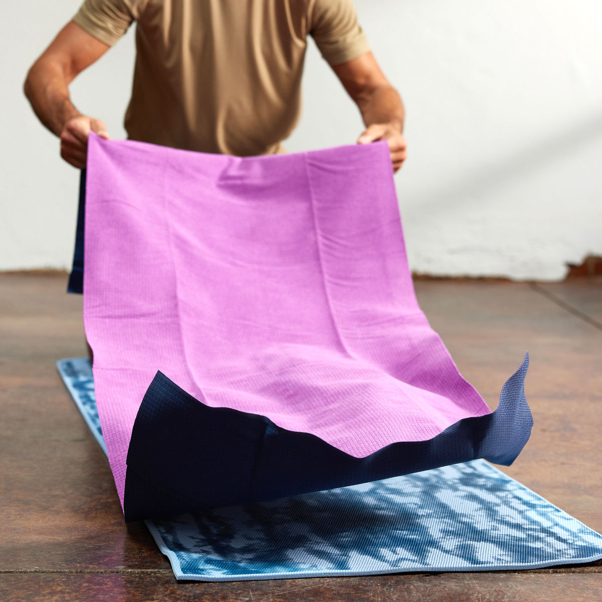 Person shaking out the No-Slip Towel on top of yoga mat