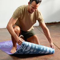 Person kneeling on the Purple Lotus Mat while unrolling it