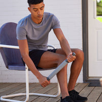 Seated Person using the Restore Deep Tissue Massage Roller on the side of the calf muscle 