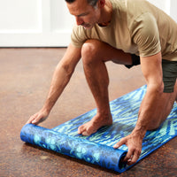 Person unrolling the Premium Reversible Divine Impressions Yoga Mat