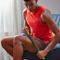 Seated person using the Restore Performance Massager on upper leg