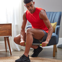Seated person using the Restore Performance Massager on calf