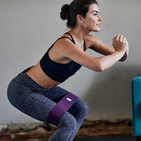 Person doing a squat using the Restore Hip Band purple