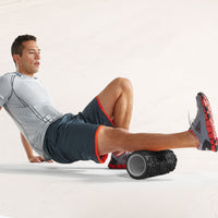 Person using the Restore Deep Tissue Performance Roller to massage 1 leg while on the ground