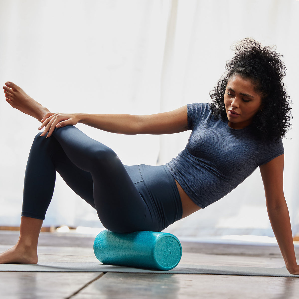 Person using the Essentials High-Density Foam Roller  to massage the upper side hip