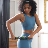 Standing person using the Restore Adjustable Massage Roller Plus on the upper side of the hip