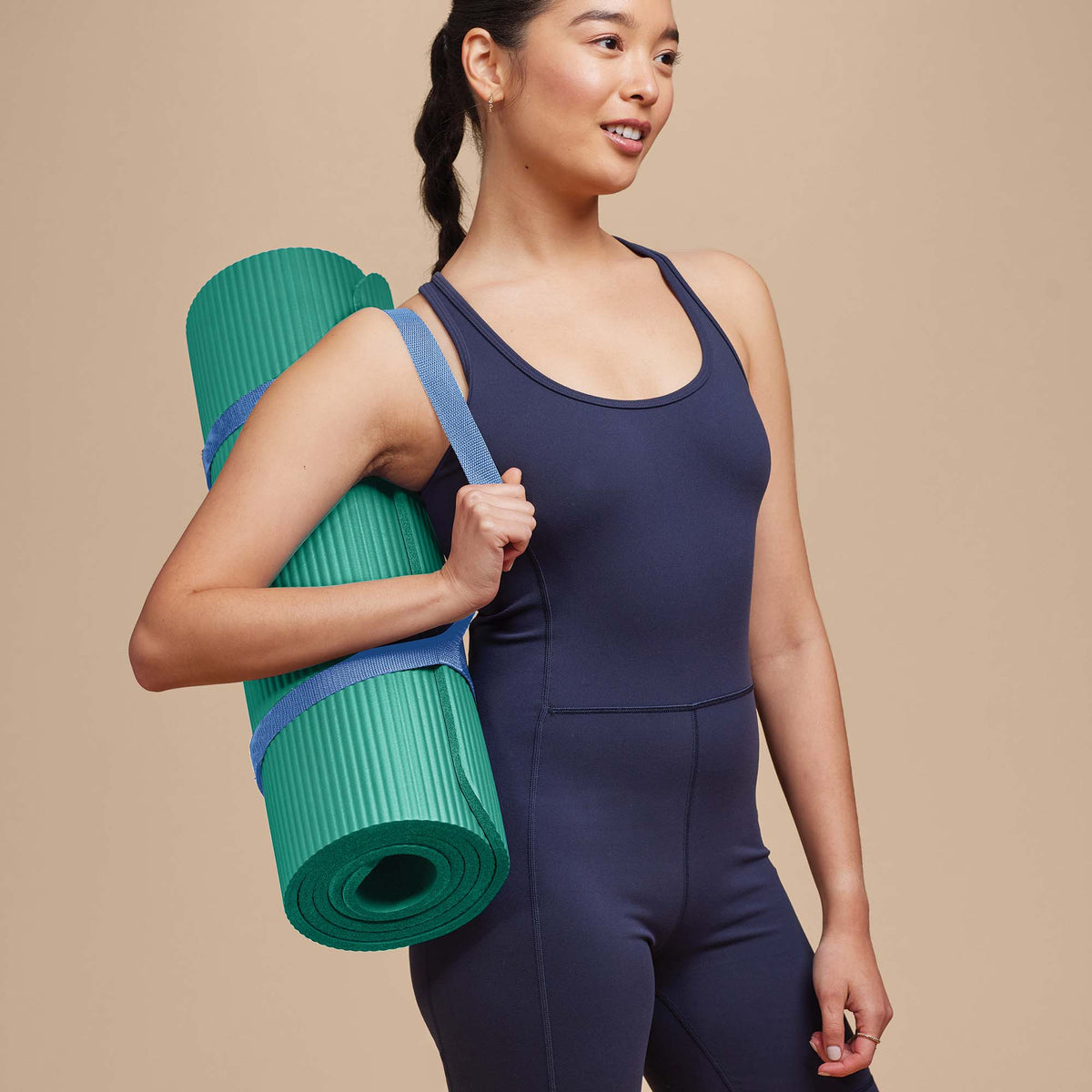 Person carrying the POPSUGAR Fitness Mat with the sling wrapped around it