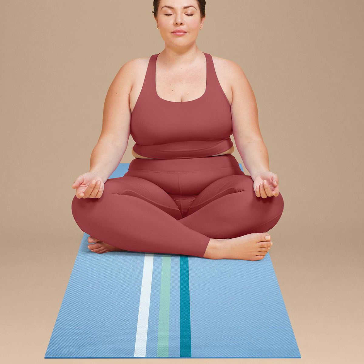 Person sitting on the POPSUGAR Premium Stripes Yoga Mat