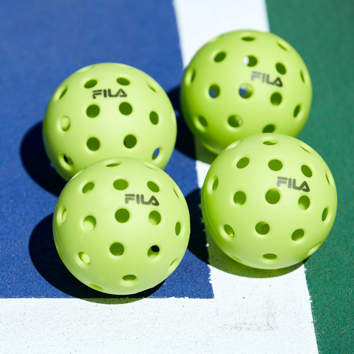 Up close of 4 Lime Pickleballs on the court