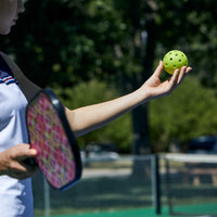 Person holding a lime pickleball getting ready to hit the ball 