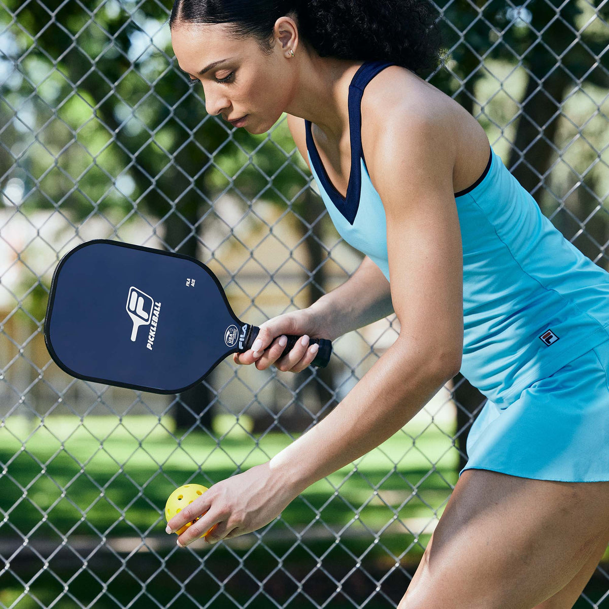 Person outside holding Graphite Pickleball Paddle getting ready to serve the ball over the net