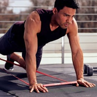 Man on fitness mat with superbands in hands