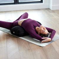 Woman lying down with black bolster under lower back