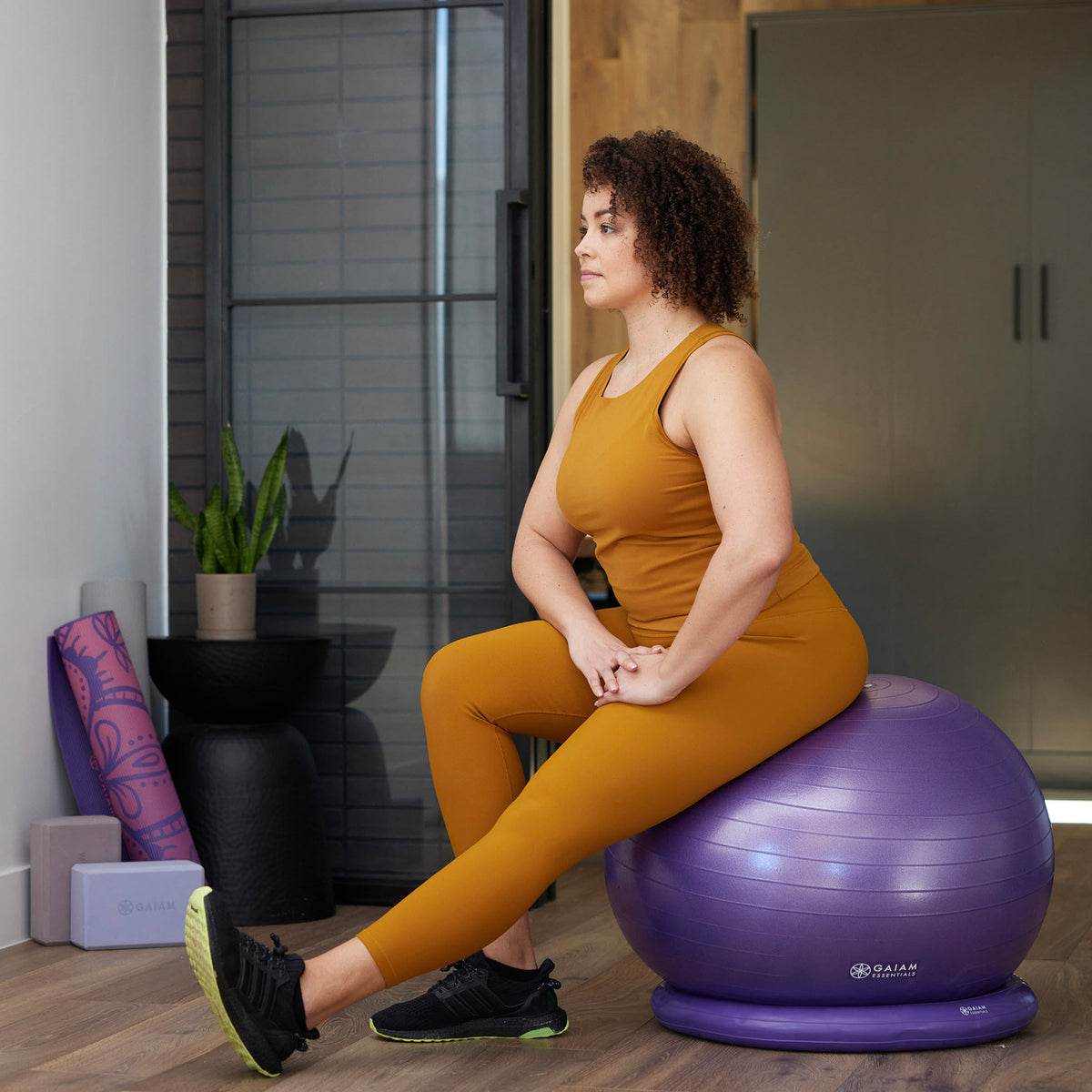 Woman seated on exercise ball stretching hamstring