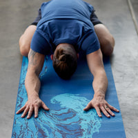 Person in childs pose on Reversible Peaceful Waters yoga mat