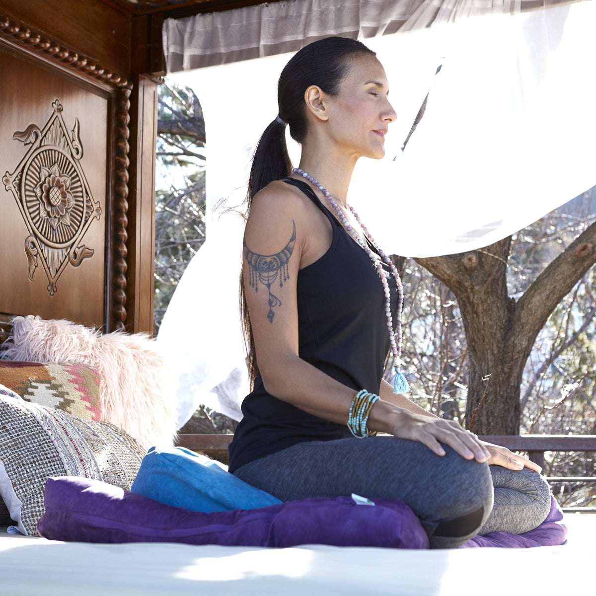 woman meditating on blue zafu cushion paired with the purple zabuton cushion